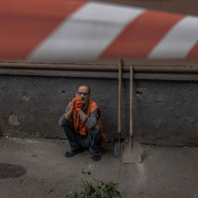 Radnik komunalnog poduzeća kraj uništene zgrade u Kijevu