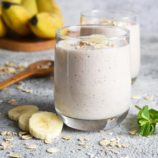 Smoothie with banana and oatmeal for breakfast on a light concrete background. Detox menu.