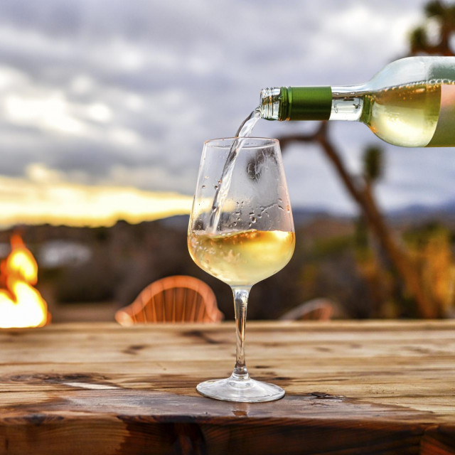 Pouring Wine with Desert Sunset and Fire Pit Backdrop