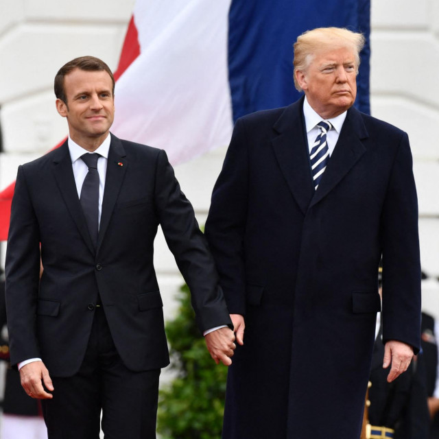 Emmanuel Macron i Donald Trump se drže za ruke, ali više izgleda da Trump vodi Macrona