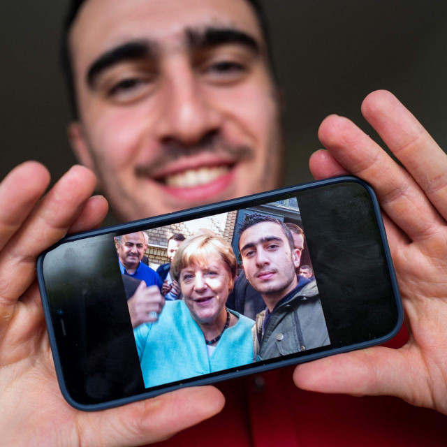 Sirijsko-njemački novinar Anas Modamani na ulicama Berlina. Anas je jedan od brojnih Sirijaca koji je 2015. došao u Njemačku iz tada ratom zahvaćene zemlje. Njegova fotografija s bivšom kancelarkom Angelom Merkel, koja mu želi dobrodošlicu, postala je viralna. Anas je jedan od brojnih Sirijaca koji želi ostati u Njemačkoj, na koncu i dobiti njemačko državljanstvo