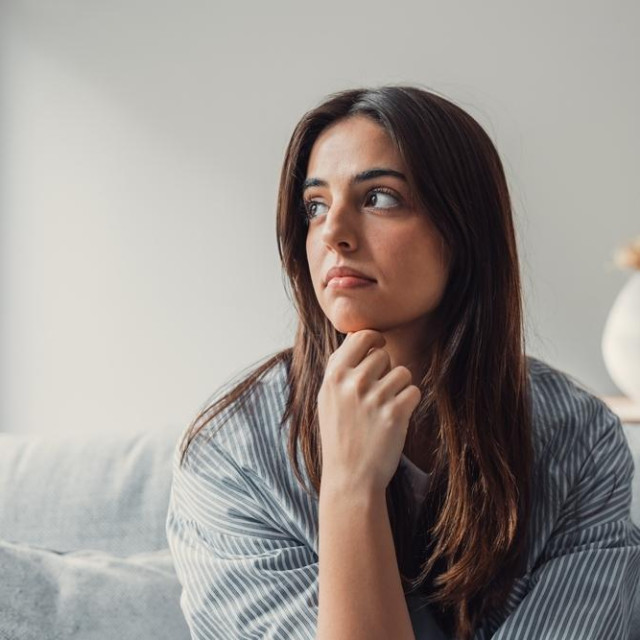 Close up of sad pensive millennial woman sit alone thinking about relationships personal problems, upset thoughtful young female lost in thoughts feel lonely depressed pondering or mourning at home