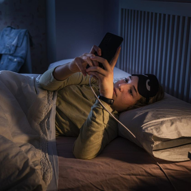 Teenage girl suffering sleeping disorders using smartphone at night