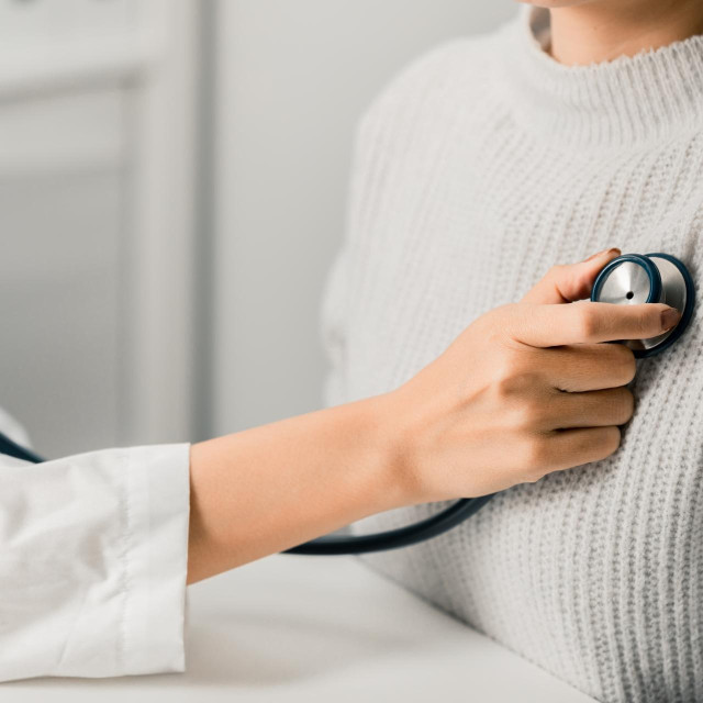 Close up of Female Doctor using stethoscope putting beat heart diagnose with patient in examination room at a hospital, check-up body, Medical and Health Care Concept.